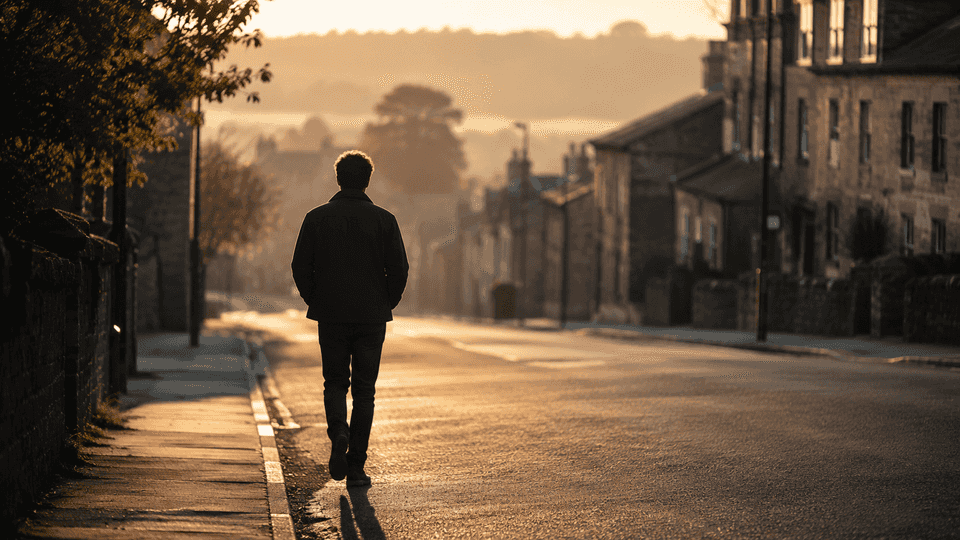 A man walking alone down a quiet street at dawn, before the world wakes up